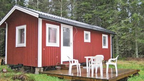 Eine rote Holzhütte mit einer Holzterrasse und weißen Plastikstühlen.