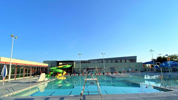 A swimming pool with a diving board, surrounded by buildings and a clear sky. - CΛsitΛ ΛrizonΛ - Tempe - Designed for LARGE FAMILIES + Kids (Tempe)