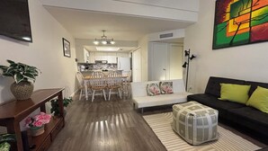 A modern living room with a sofa, ottoman, and a dining area with chairs and a table. - CΛsitΛ ΛrizonΛ - Tempe - Designed for LARGE FAMILIES + Kids (Tempe)