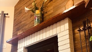 A fireplace with a brick surround, a wooden mantel, and a vase with flowers. - CΛsitΛ ΛrizonΛ - Tempe - Designed for LARGE FAMILIES + Kids (Tempe)