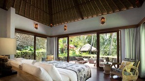 A spacious bedroom with a large bed, a wooden nightstand, a chair, and a view of the garden through large windows. - Elegant, Intimate, Luxury Contemporary Balinese Villa  In a Traditional Village  (Kemenuh, Sukawati,)