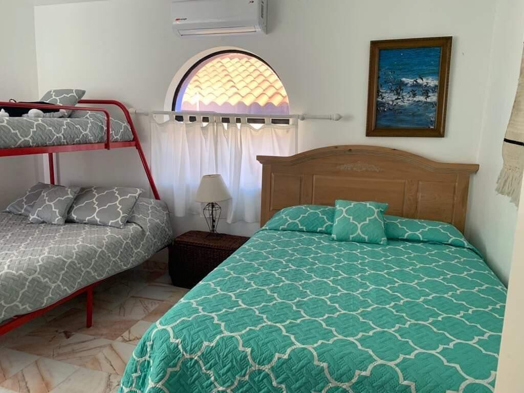 Una stanza con un letto a castello, un letto singolo, una lampada e un quadro appeso al muro.