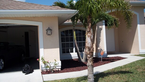 A residential house with a garage, a palm tree, and a well-maintained lawn. - beautiful homeaway , 2815 sw 29th pl (Cape Coral)