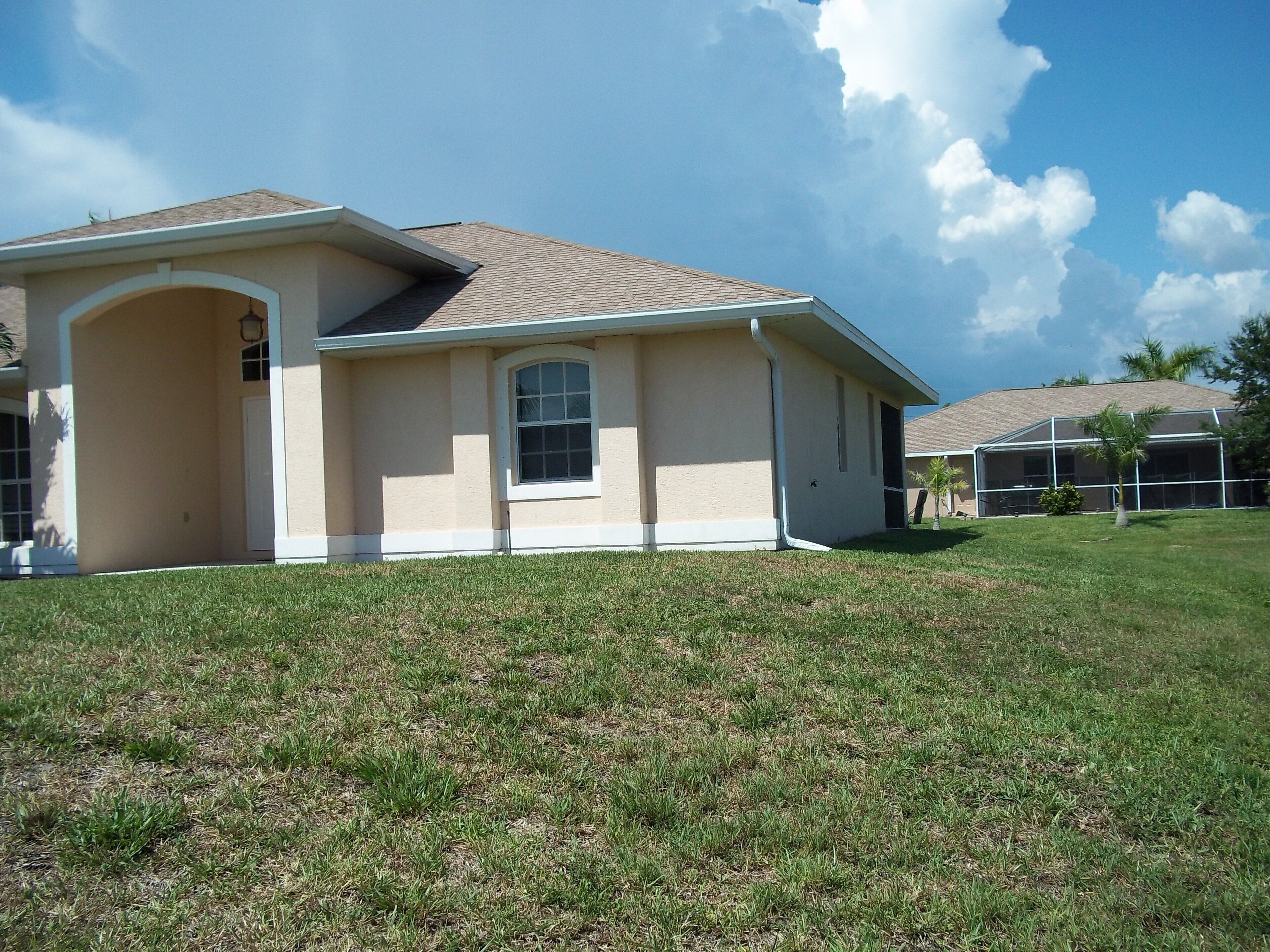 A single-story house with a beige exterior, a front porch, and a covered patio area.
