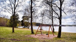 A swing set in a park with a lake in the background. - 2 bedroom lovely home in Hyltebruk (Hyltebruk)