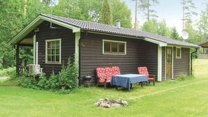 Eine rustikale Holzhütte mit Veranda, Tisch mit Tischdecke und Feuerstelle.