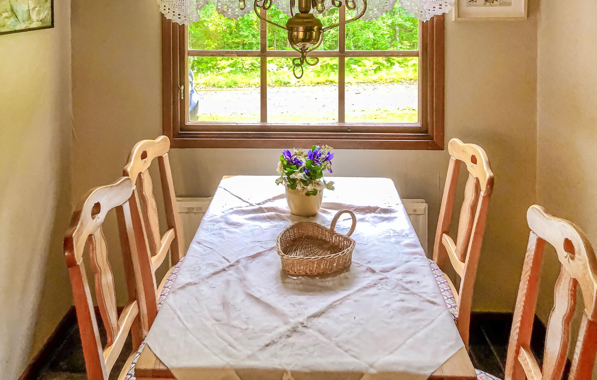 Une table à manger recouverte d’une nappe blanche, un panier en osier et un vase rempli de fleurs.