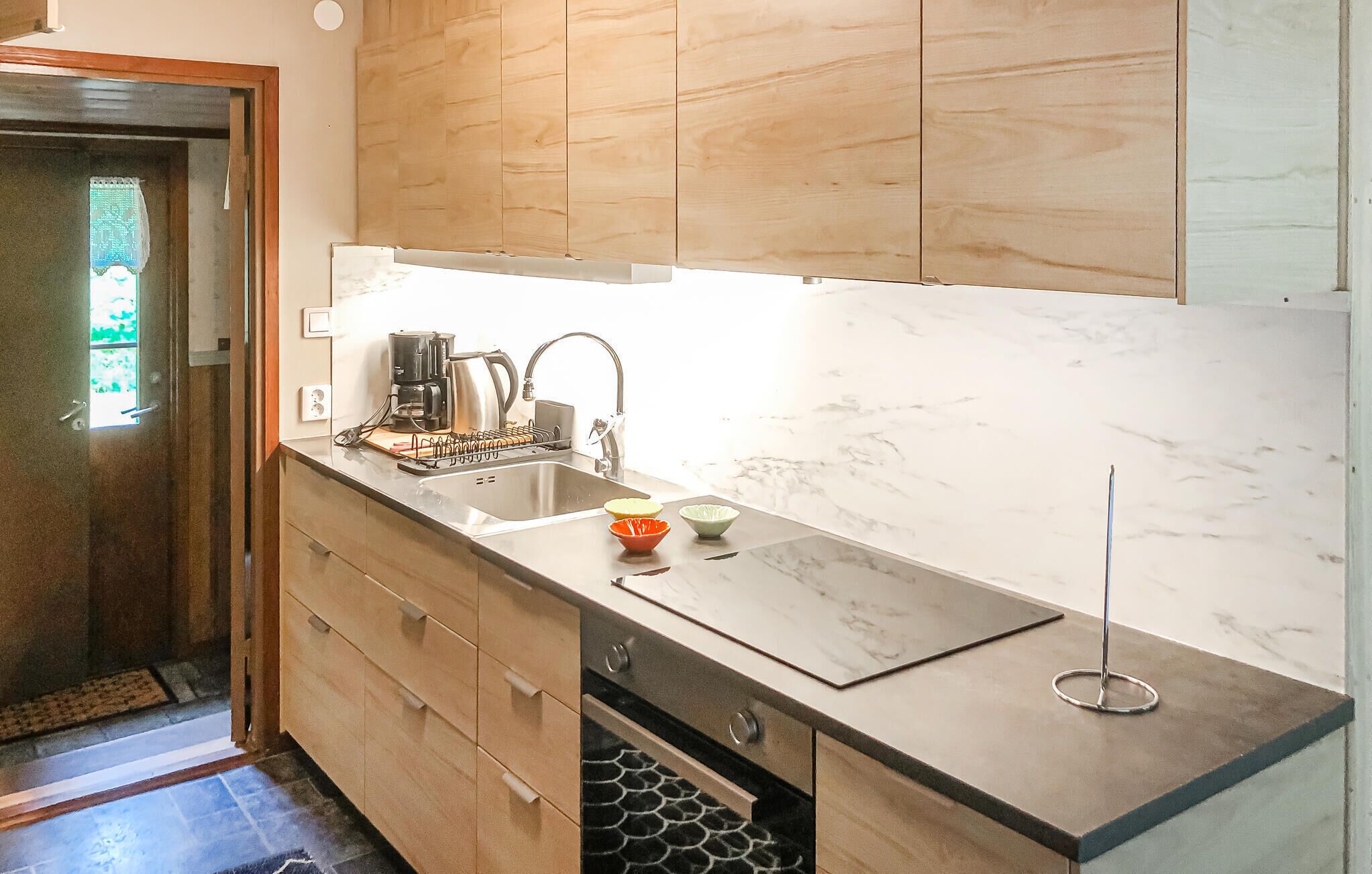 Une cuisine moderne avec des meubles en bois, un évier en acier inoxydable et un dosseret en marbre.