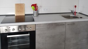 Een moderne keuken met grijze kastjes, een roestvrijstalen fornuis en een ingebouwde oven.