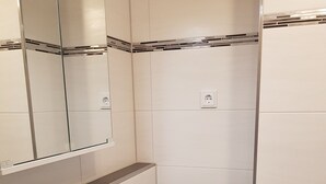 Een badkamer met een witte wasbak, een spiegel erboven en een blauwe handdoek aan een rek.