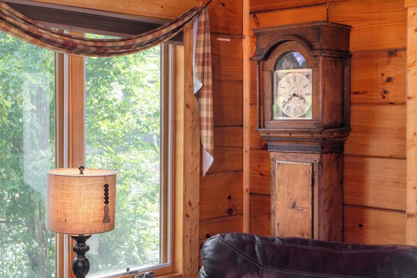 Ein Holzinnenraum mit einem großen Fenster, einer Uhr und einer Lampe.