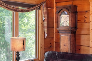 Een houten interieur met een groot raam, een klok en een lamp.