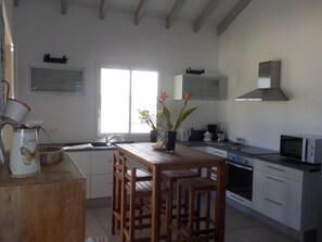 Enjoy meals in this kitchen with a dining table and chairs, white cabinets, a range hood, and microwave.