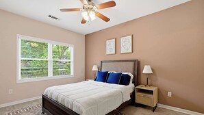 A bedroom with a bed, nightstands, a ceiling fan, and a window with blinds. - West Midtown 2BR (1st Floor) w/ Free parking (Atlanta)