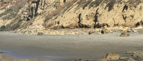 A rocky beach with a large cliff in the background.