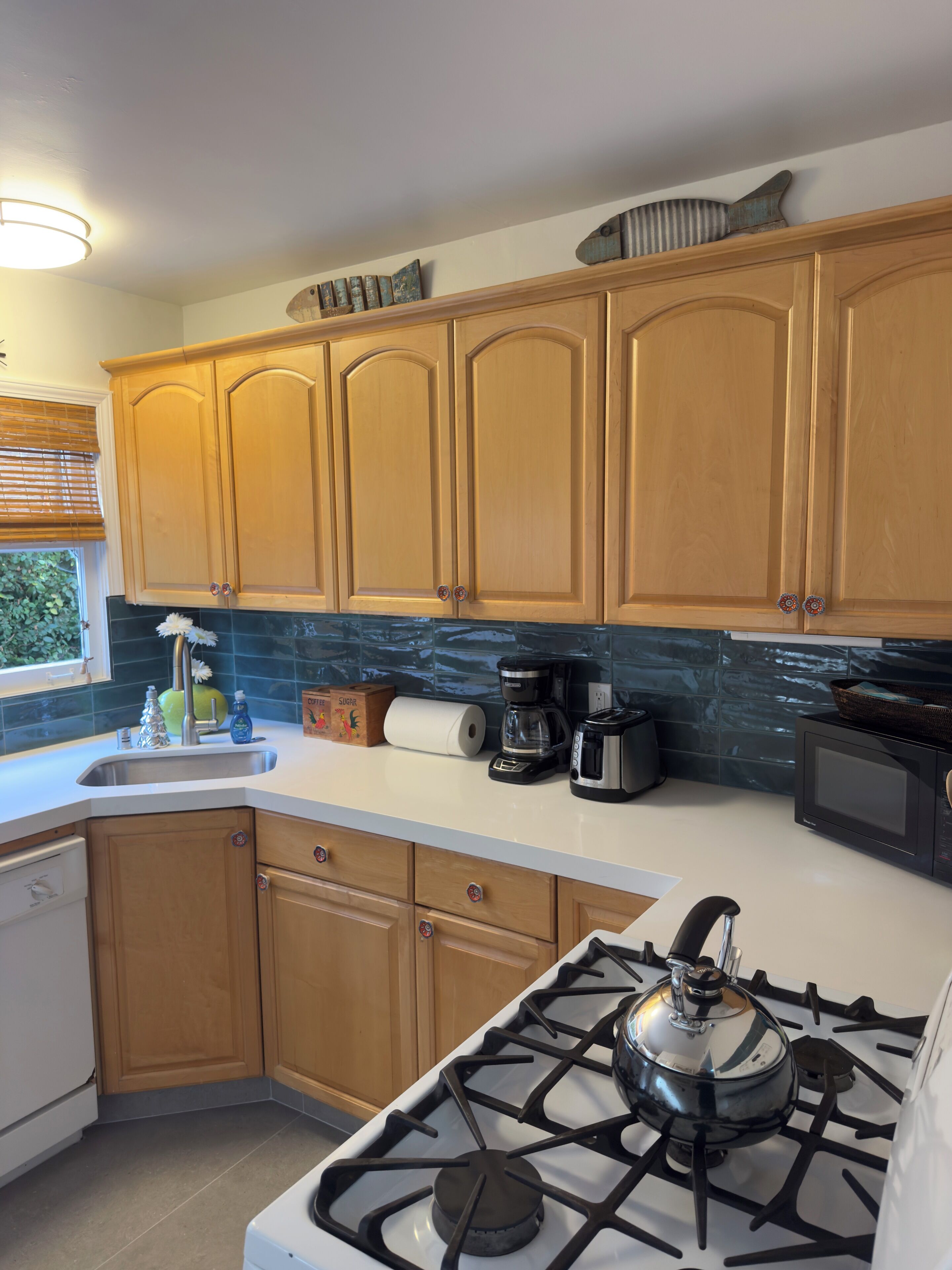 A kitchen with wooden cabinets, a gas stove, a microwave, and a coffee maker.