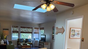 A dining area with a round table, white chairs, and a ceiling fan. - La Jolla Shores Beach Cottage (La Jolla)