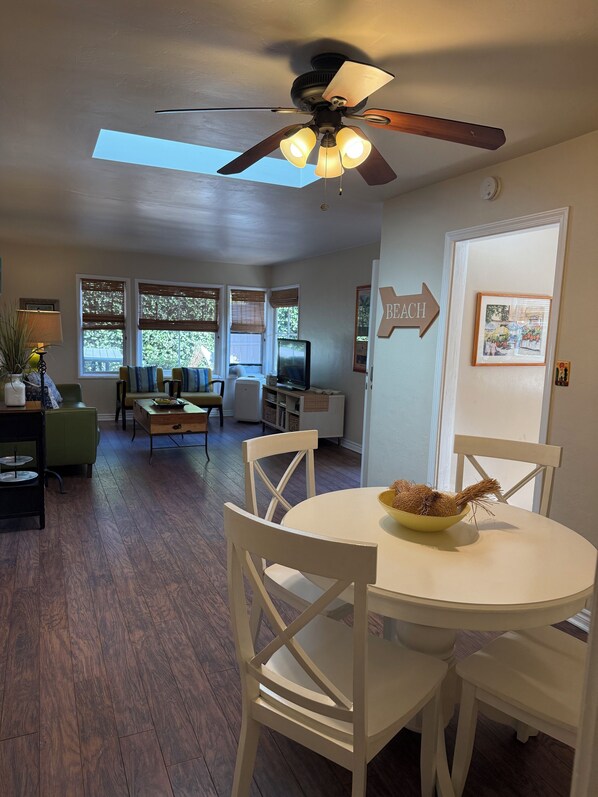 A dining area with a round table, white chairs, and a ceiling fan.