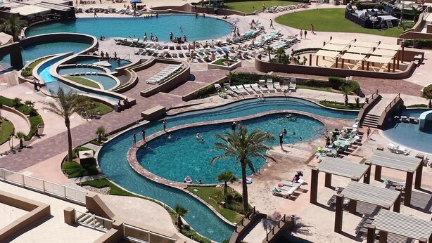 Een resort met meerdere zwembaden, een strand en uitzicht op de oceaan.