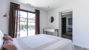 A bedroom with a large bed, a desk, and a view of an outdoor pool. - Superb new contemporary villa with private pool 400 m from the sea  (Agde)
