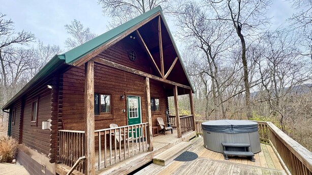 Une cabane en bois avec une véranda, un jacuzzi et une terrasse.