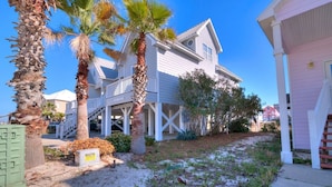 A two-story house with a covered porch and a sandy yard. - Spectacular Gulf Views in Gated Community with Pool and Hot Tub. Quite beach!   (Gulf Shores)