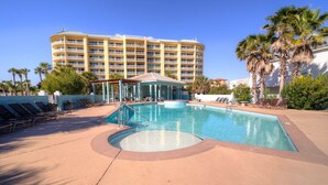 A pool area with lounge chairs, a small pavilion, and a large hotel building in the background. - Spectacular Gulf Views in Gated Community with Pool and Hot Tub. Quite beach!   (Gulf Shores)