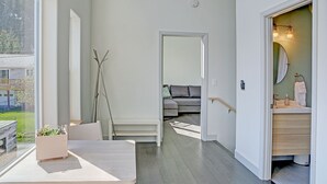A modern interior with a dining area, a sofa, and a bathroom with a mirror and sink. - Modern Accommodations with Luxurious View (Seward)