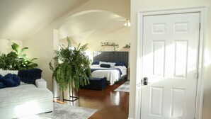 A bedroom with a bed, a white door, and a hallway. - Botanical Loft in Amish Country, King Bed, Jetted Tub & Garden Patio (Bird-In-Hand)