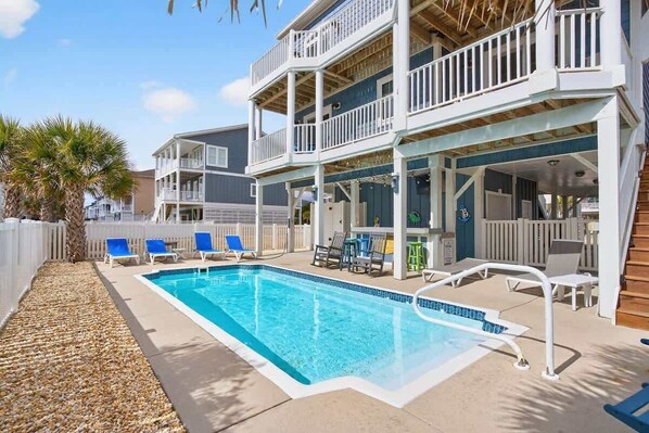 A two-story building with a pool, outdoor seating, and a covered patio area.