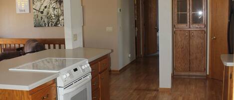 A kitchen with wooden cabinets, a white stove, and a patterned rug.