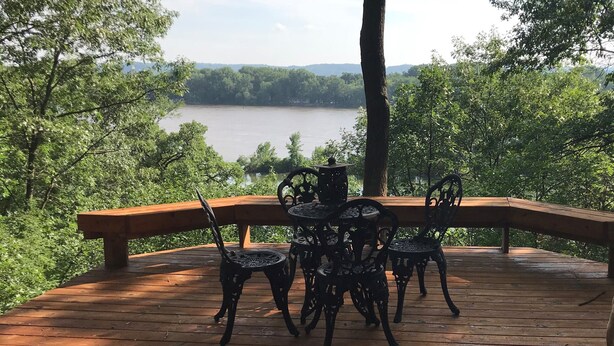 A wooden deck with a table and chairs overlooking a lake.