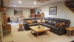 A living room with a leather sofa, a wooden coffee table, and a dining area in the background.