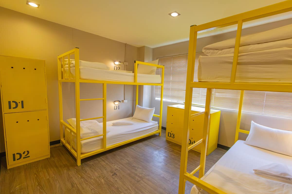 Una habitación con literas, un armario y una ventana con persianas.