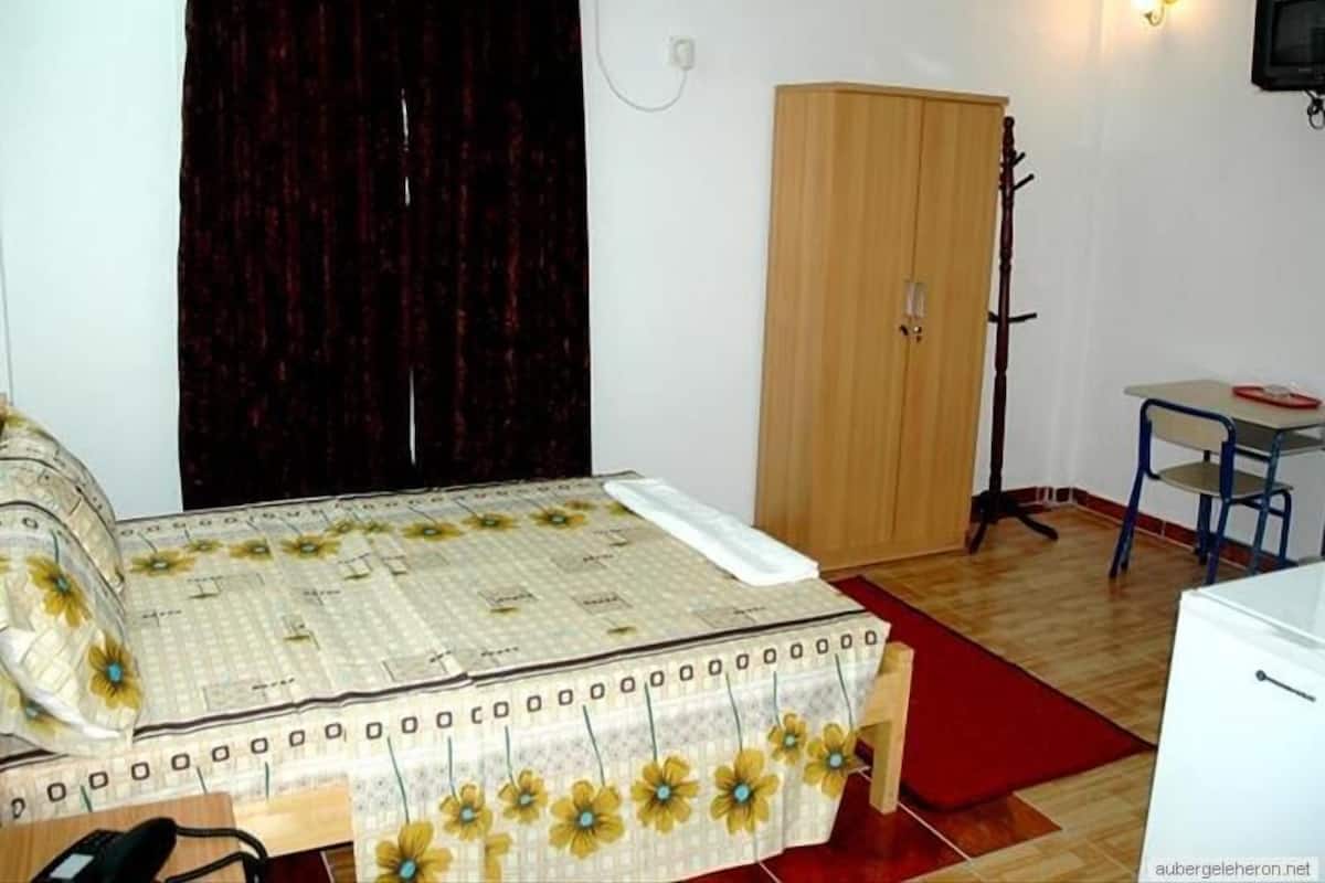 Un dormitorio con cama, armario, escritorio y silla.