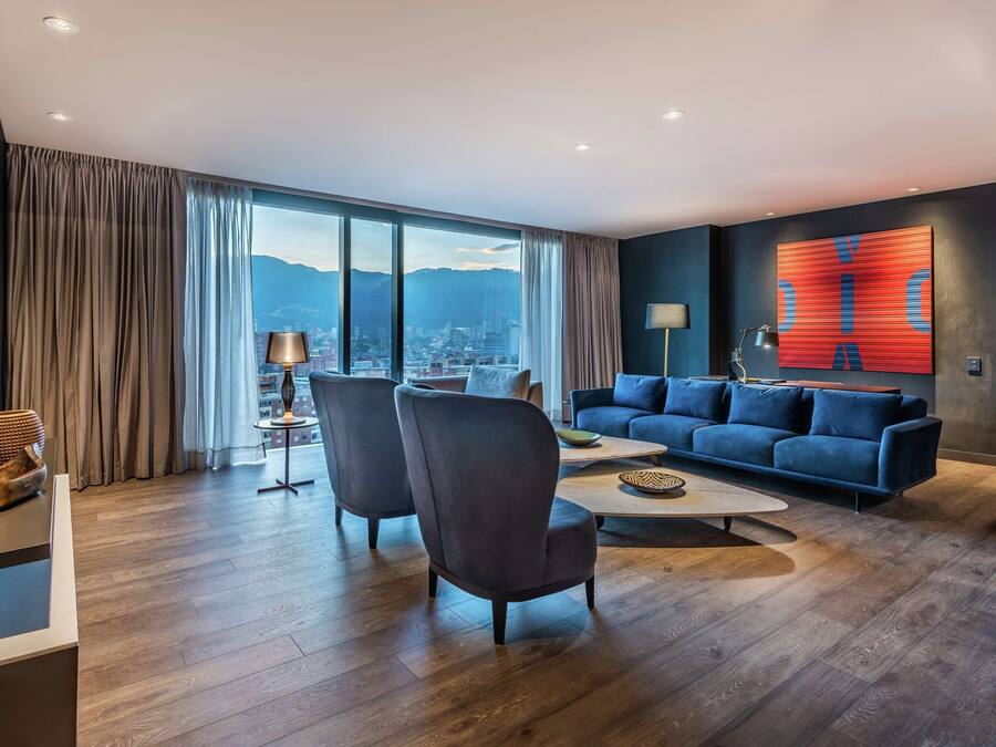 A modern living room with a large window, a blue sofa, two armchairs, and a coffee table.