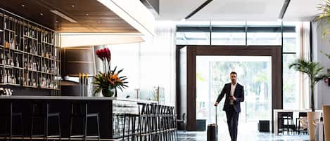Un hall d’hôtel moderne doté d’un bar, de coins salon et d’une grande fenêtre offrant une vue panoramique.