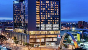 A modern hotel with a prominent Hilton sign, multiple floors, and a distinctive arched entrance.