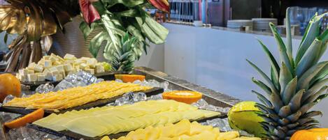 A buffet with various food items like cheese, fruits, and meats.