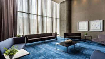 Un salon moderne avec une moquette bleue, des canapés foncés, une table basse et deux œuvres d’art encadrées accrochées au mur.