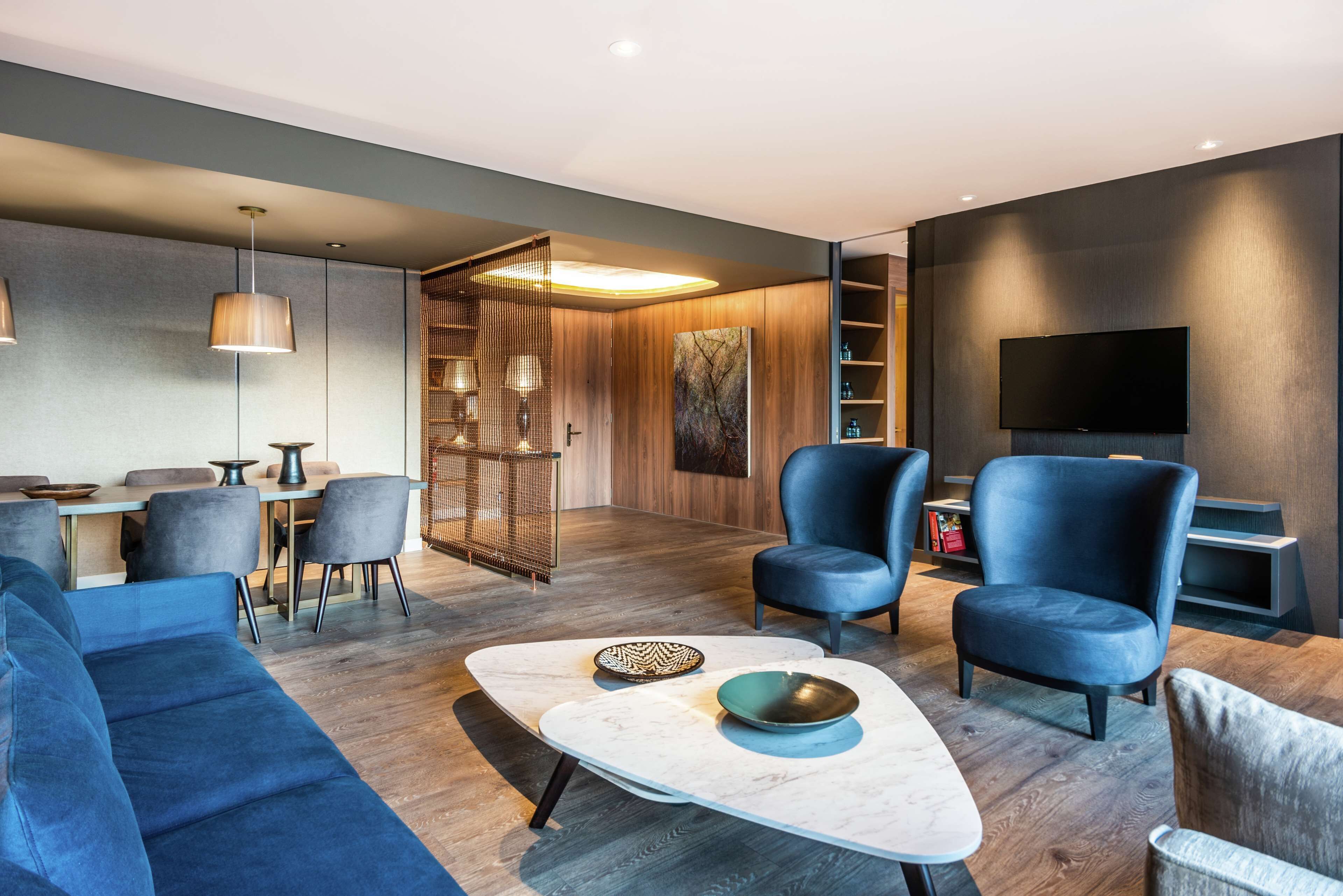 A modern living room with a sofa, chairs, a coffee table, and a TV.