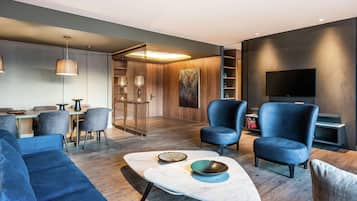 A modern living room with a sofa, chairs, a coffee table, and a TV.