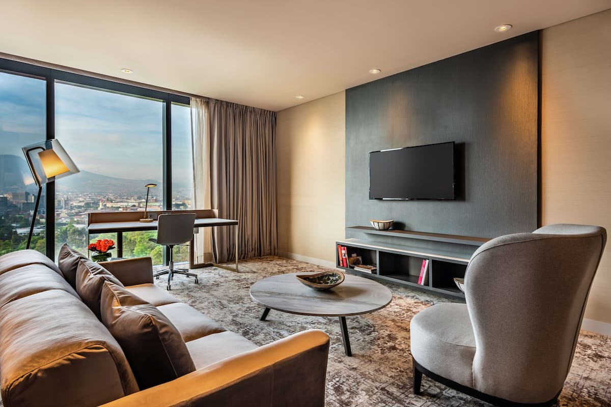 Una sala de estar moderna con un sofá, un sillón, una mesa de centro y un televisor de pantalla plana montado en la pared.