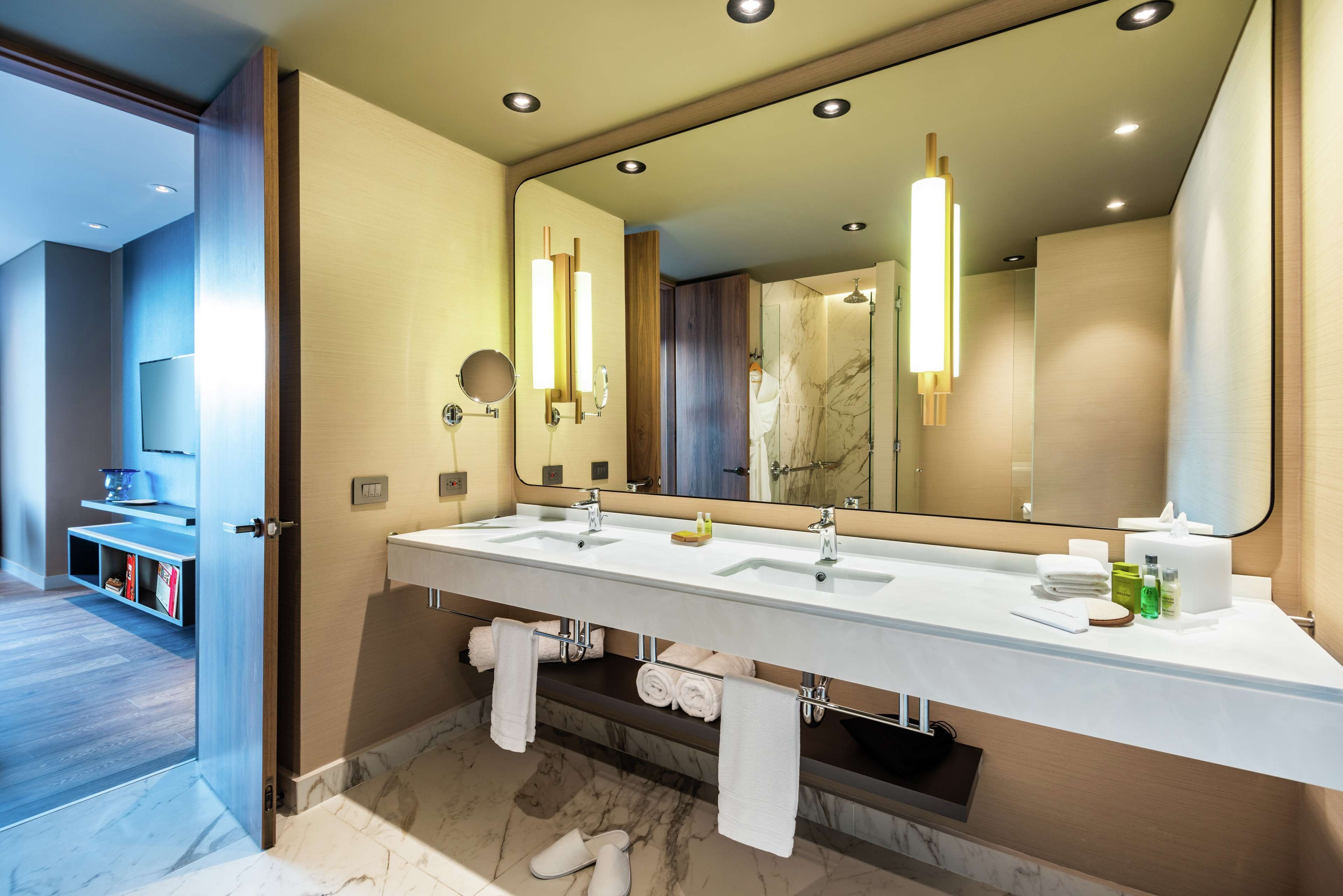Une salle de bain moderne avec un grand miroir, deux lavabos et un meuble-lavabo.