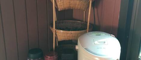 A kitchen area with a coffee maker, a basket, and various kitchen items on a wooden shelf.