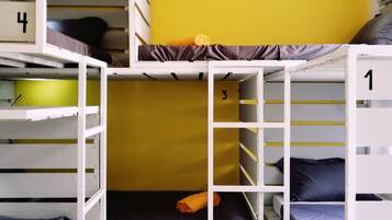 A multi-level bunk bed room with numbered beds, a yellow wall, and a tiled floor.