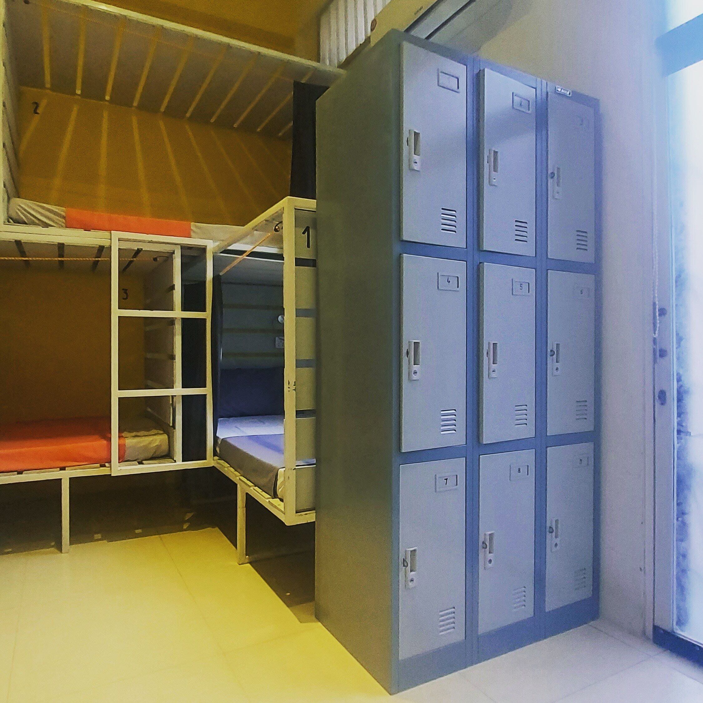 A dormitory room with bunk beds and a set of lockers.