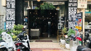 La entrada de un hostal y bar en la azotea llamado "The Place", con un cartel que anuncia servicios como dormitorios, bar en la azotea y tours guiados.