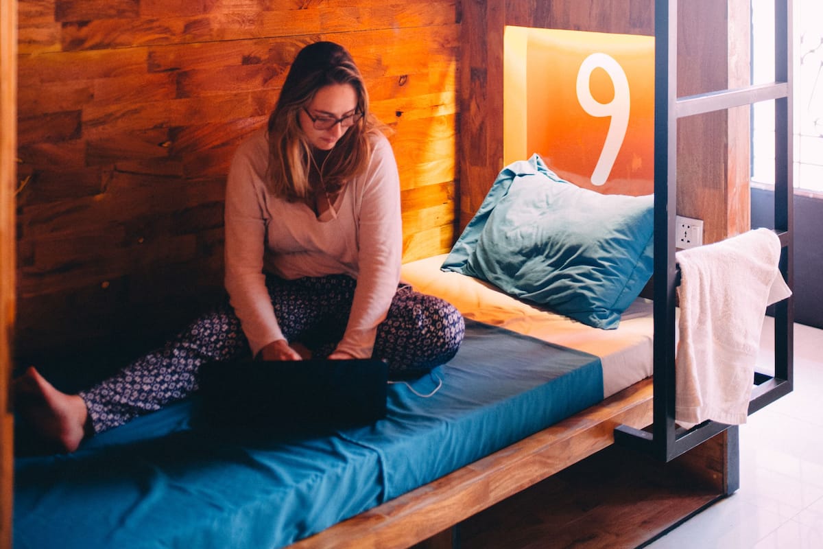 A bunk bed room with a wooden wall, a bed with blue and grey bedding, and a number '9' sign on the wall.