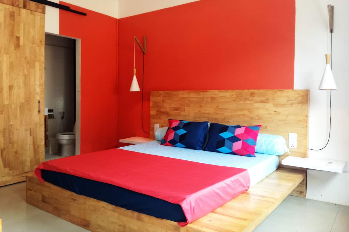A bedroom with a wooden bed, red walls, and a white bedside table.